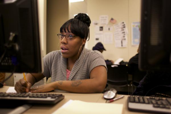 A Black woman works at a computer at YWCA's Opportunity Place