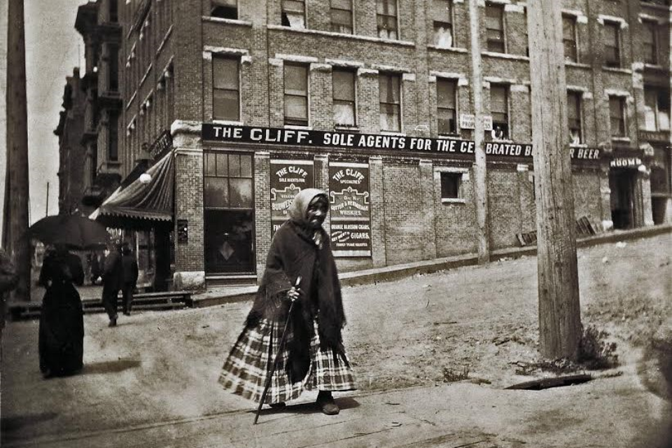 A black and white photo of Princess Angeline walking around early Seattle