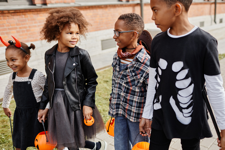 Photo of four black children dressed in halloween costumes going trick or treating