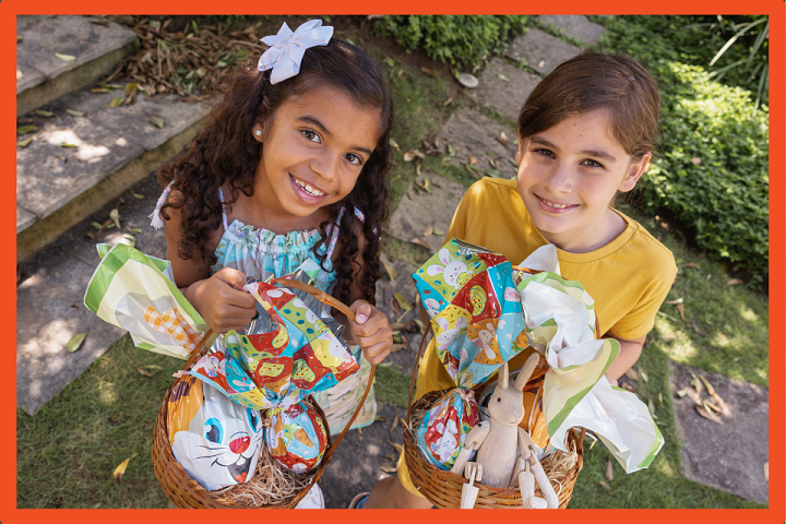 A photo of two girls holding gift baskets, smiling up at the camera