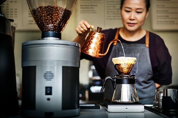 A woman makes coffee in a cafe